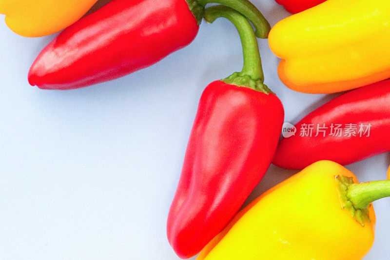 一小群完整的，红色和黄色的迷你辣椒(Capsicum annuum)，白色背景上的绿色茎，特写图像，抬高视图，复制空间